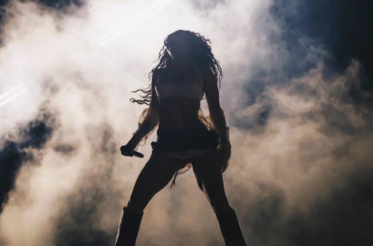 Charli XCX fighting her way through the smoke that symbolises all the barriers faced by women throughout time.